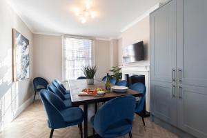 uma sala de jantar com uma mesa e cadeiras azuis em Elliot Oliver - Laverham House - Stunning 6 Bedroom Regency House With Parking em Cheltenham