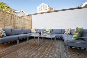 a patio with blue couches and a table at Elliot Oliver - Laverham House - Stunning 6 Bedroom Regency House With Parking in Cheltenham