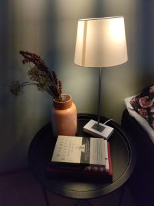 einen Tisch mit einer Lampe, einem Buch und einer Vase in der Unterkunft Villa Astrid in Pietarsaari