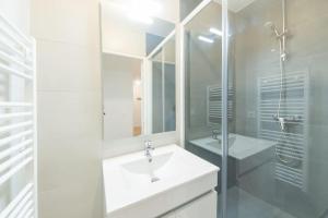 ein weißes Badezimmer mit Waschbecken und Spiegel in der Unterkunft Suite Moderne Familiale 8 Pers - Disney 10m - 2 SDB in Bussy-Saint-Georges + 9 Fotos