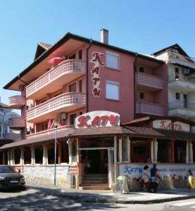 a pink building with people standing outside of it at Къща за гости КАТИ in Kiten