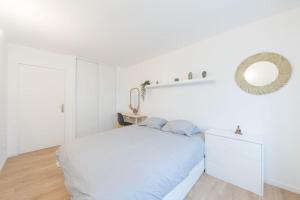 ein weißes Schlafzimmer mit einem Bett und einem Spiegel in der Unterkunft Suite Moderne Familiale 8 Pers - Disney 10m - 2 SDB in Bussy-Saint-Georges