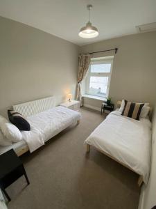 sypialnia z 2 łóżkami i oknem w obiekcie Newly renovated, hi-spec three bed, forest view home w mieście Cwmcarn