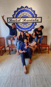 a group of people sitting on benches in front of a sign at Hostel Mandala in Anjuna