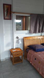 1 dormitorio con 1 cama y 1 mesa con lámpara en Nouveau logement T2 avec vue sur mer et montagne en Sainte-Rose