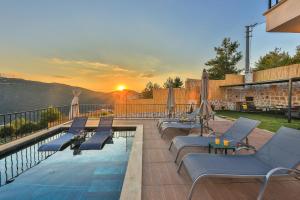 una piscina con tumbonas y puesta de sol en Villa mirador, en Kas