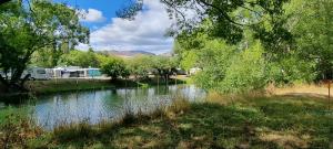 a river with trees and a rv in the background at Home Away from Home - Waitaki Lakes Apartment A5 in Otematata