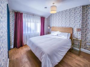 um quarto com uma cama branca e papel de parede azul e rosa em The Kinsale 4 Center em Kinsale