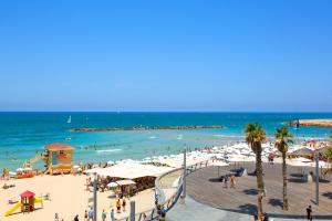 a beach with a crowd of people and the ocean at 9 Sderot Chen - By Beach Apartments TLV in Tel Aviv