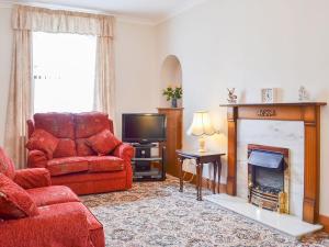 a living room with a red couch and a fireplace at Number 12 in Portknockie