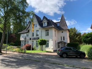 une voiture garée devant une grande maison dans l'établissement Hotel Seeufer, à Plön