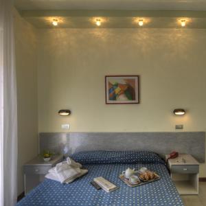 リッチョーネにあるHotel Reggianaのベッドルーム1室(ベッド1台、食料品のトレイ付)