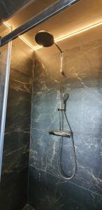 y baño con ducha y pared de mármol negro. en Héthatár Wellness Vendégház - Gerle, en Pusztavacs