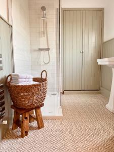 uma casa de banho com um cesto de toalhas num banco em The Cottage, Yew Tree Farm Holidays, Tattenhall, Chester em Tattenhall