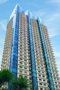 a tall building with palm trees in front of it at Astoria Plaza in Manila