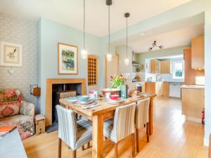 a kitchen and living room with a wooden table and chairs at Oak Cottage in Saxmundham