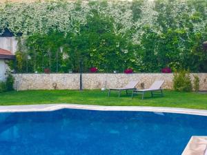 a blue swimming pool with two chairs and a wall at Ara Town House in San Giovanni la Punta