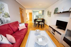 ein Wohnzimmer mit einem roten Sofa und einem Tisch in der Unterkunft Apartamentos Cean Bermudez in Gijón