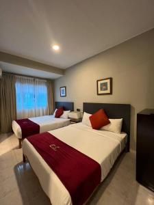 um quarto de hotel com duas camas e uma janela em Perdana Serviced Apartment & Resorts em Kampung Padang Masirat