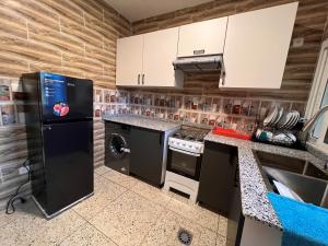 a kitchen with a black refrigerator and a dishwasher at SMB-gn RÉSIDENCE LAMBANDJI in Conakry