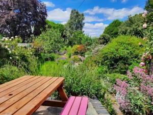 um banco de madeira sentado no meio de um jardim em Charming Grade 2 Listed cottage, Upton-upon-Severn em Upton upon Severn