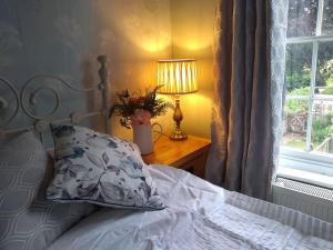 a bed with a pillow and a table with a lamp at Charming Grade 2 Listed cottage, Upton-upon-Severn in Upton upon Severn