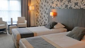 um quarto de hotel com duas camas e uma mesa e cadeiras em Hotel Asteria em Venray