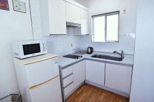 una pequeña cocina blanca con fregadero y microondas en Ever Rose Pension, en Namhae