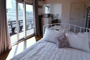 a bedroom with a white bed with pillows and a balcony at Ever Rose Pension in Namhae