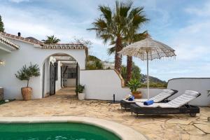 una piscina con due sedie e un ombrellone accanto a una casa di Marvellous Private Villa Cómpeta a Cómpeta