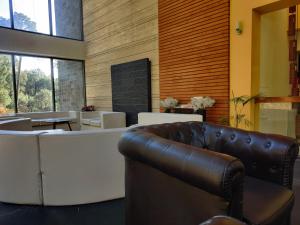 una sala de espera con una silla de cuero y mesas en Wood Creek Resort & Spa Kasauli en Kasauli