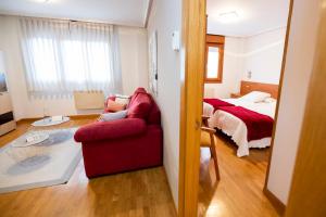 a living room with a red couch and a bed at Apartamentos Cean Bermudez in Gijón