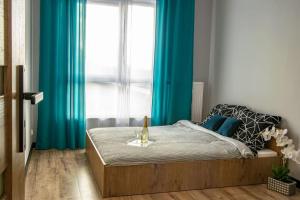 a bedroom with a bed with blue curtains at Apartament Nowa Grunwaldzka in Suwałki