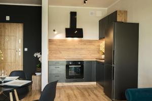 een keuken met een koelkast en een tafel met stoelen bij Apartament Nowa Grunwaldzka in Suwałki