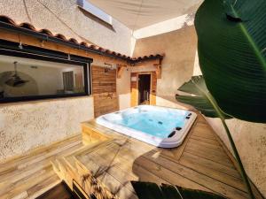 uma banheira de hidromassagem num piso de madeira com uma planta em Cocon Nature Montpellier - Jacuzzi & Sauna - 300m du Tramway em Castelnau-le-Lez