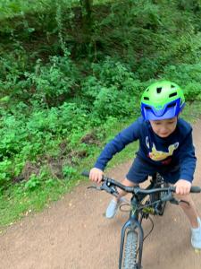 a young boy wearing a helmet riding a bike at Thatch Close Cottages in Ross on Wye