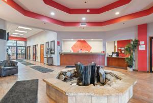 an office lobby with a fireplace in the middle at Ramada by Wyndham Sioux Falls Airport - Waterpark Resort & Event Center in Sioux Falls