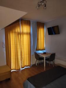 a living room with a table and yellow curtains at Your Place Borovets in Borovets