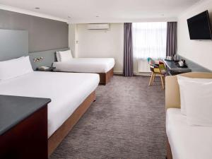 a hotel room with two beds and a desk at Mercure Chester Abbots Well Hotel in Chester