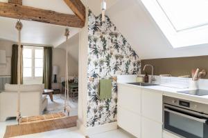 a kitchen with white cabinets and a floral wallpaper at Séjours Maison Baluchon in Chaumont