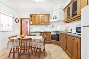 una cucina con armadi in legno, tavolo e sedie di Casa da Bia by OCvillas ad Albufeira