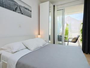 a white bedroom with a bed and a chair at Palm Tree Apartments in Dubrovnik +29 photos