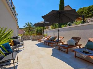 a patio with chairs and umbrellas on a patio at Palm Tree Apartments in Dubrovnik