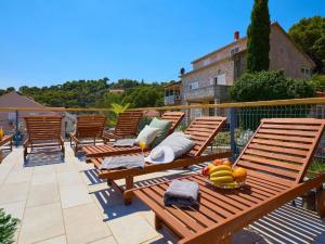 a row of wooden chairs on a patio with a bowl of fruit at Palm Tree Apartments in Dubrovnik