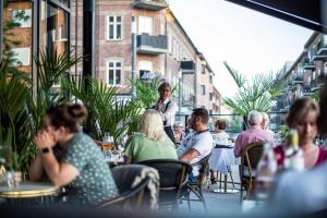 eine Gruppe von Personen, die in einem Restaurant im Freien sitzen in der Unterkunft Statt Hassleholm BW Signature Collection in Hässleholm