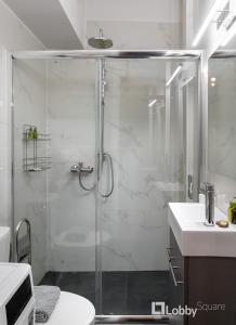 La salle de bains est pourvue d'une douche avec une porte en verre. dans l'établissement CityLiv Apartment by LobbySquare, à Athènes