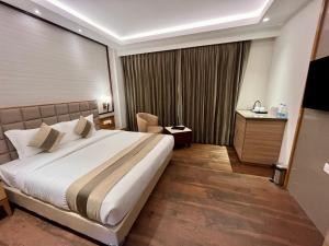 a hotel room with a large bed and a chair at ANNTILIA INN in Ludhiana