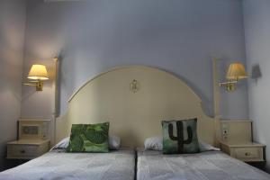 1 dormitorio con 2 camas y 2 lámparas en la pared en Hotel Harrison Etxea en Amorebieta-Etxano