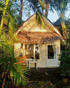 a cottage with a thatched roof and a white door at Saffron On The Sea Resort in Ko Chang