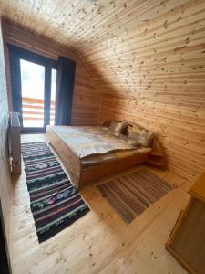 een slaapkamer met een bed in een houten kamer bij Aroa Mountain in Zărneşti